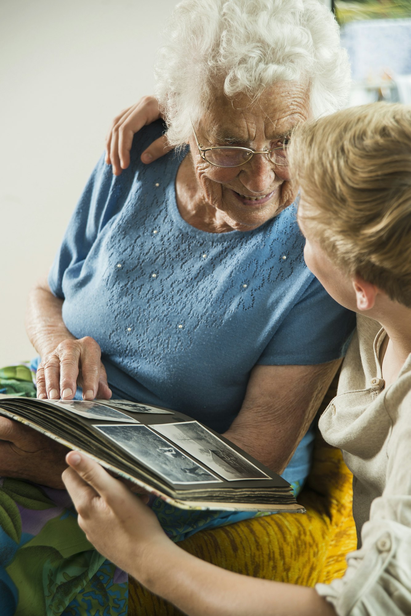 Grandmother sharing old stories with her grandson as they look through a photo album.